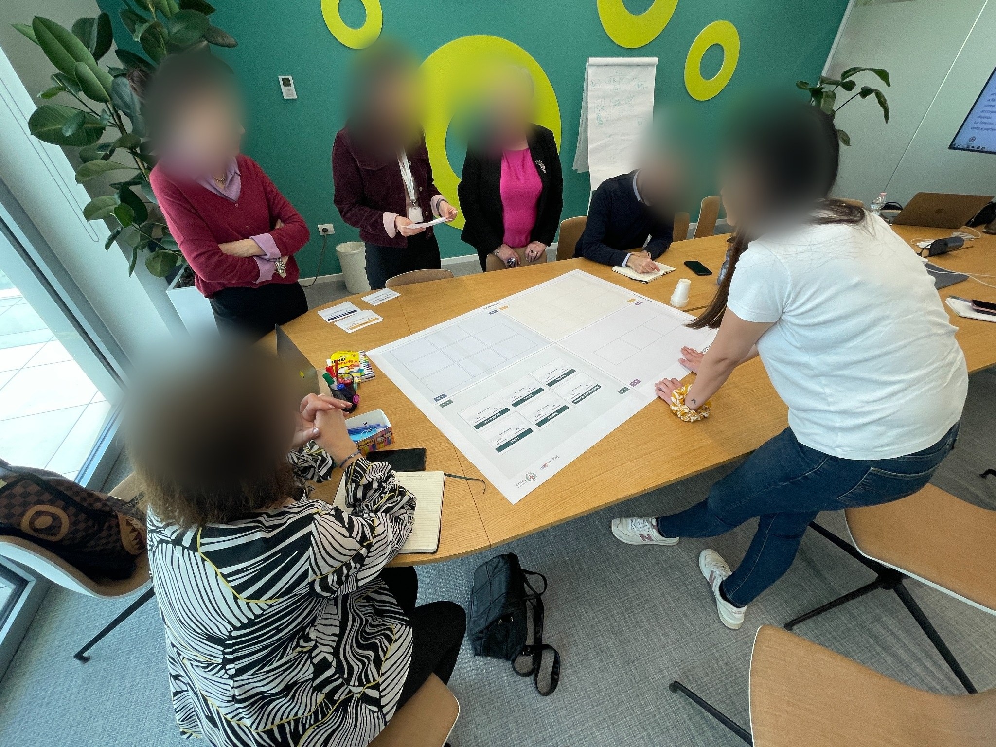 Photograph of the taxonomy workshop: a physical matrix of thematic areas, service volumes and visit data laid out on a table.
